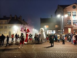 Mikołaj i Śnieżynka na szczudłach prowadzą paradę dzieci przez żorski Rynek 