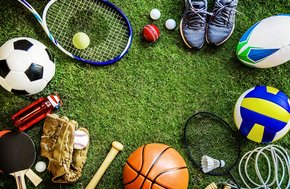 Na grafice sprzęt sportowy leżący na zielonej murawie. M.in. kij do baseballa, rakieta tenisowa, buty sportowe i piłki