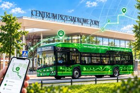 Zielony autobus Bezpłatnej Komunikacji Miejskiej przed Centrum Przesiadkowym w Żorach z grafiką telefonu i symbolami lokalizacji, nawiązującymi do śledzenia pojazdów w aplikacji myBUS online.