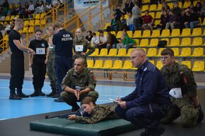 Uczniowie w mundurach podczas strzelania z broni laserowej w ramach Międzypowiatowa Olimpiada Bezpieczeństwa w Żorach 