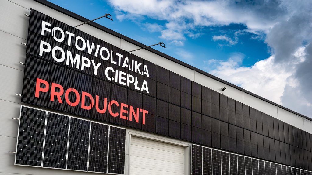 Fragment elewacji zakładu firmy JBG-2 Sp. z o.o. z napisami: fotowoltaika, pompy ciepła, producent