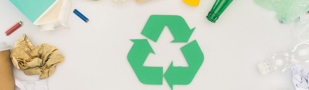 Widok z góry na śmieci różnego rodzaju leżące wokół zielonego znaku recyklingu. Stock images by Depositphotos